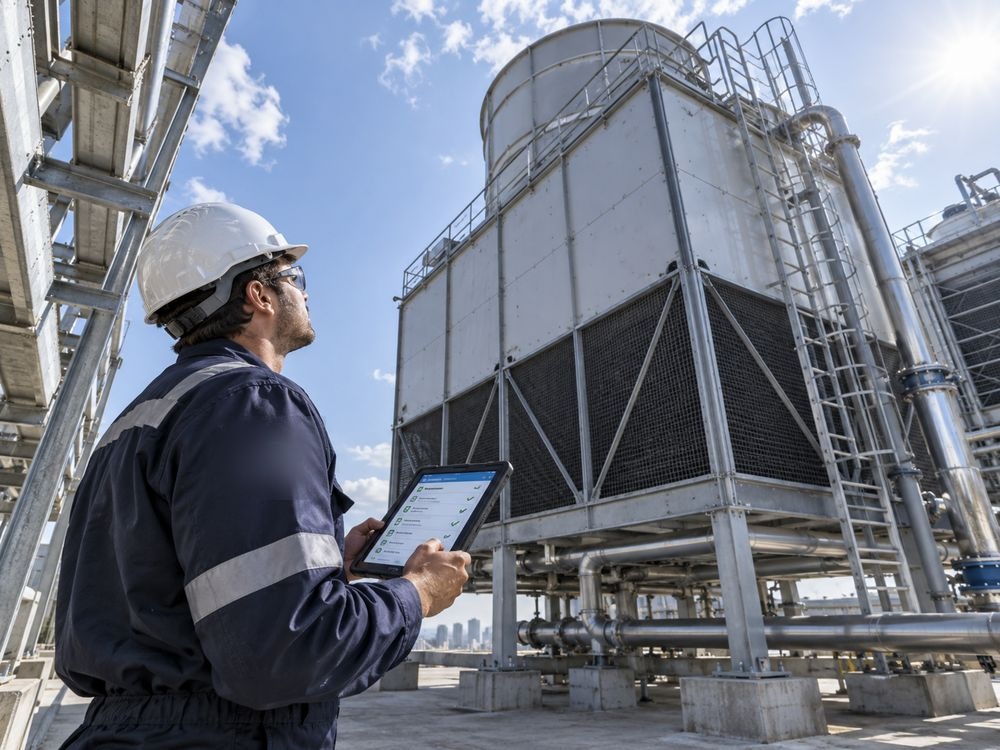 Técnico con uniforme de marca sosteniendo tablet con checklist frente a una torre de enfriamiento